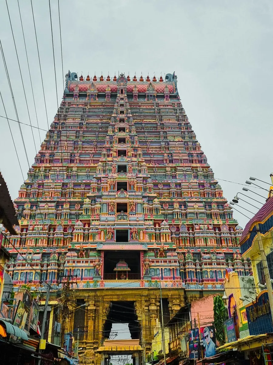 A tall, colourful temple gopuram rising above a busy street